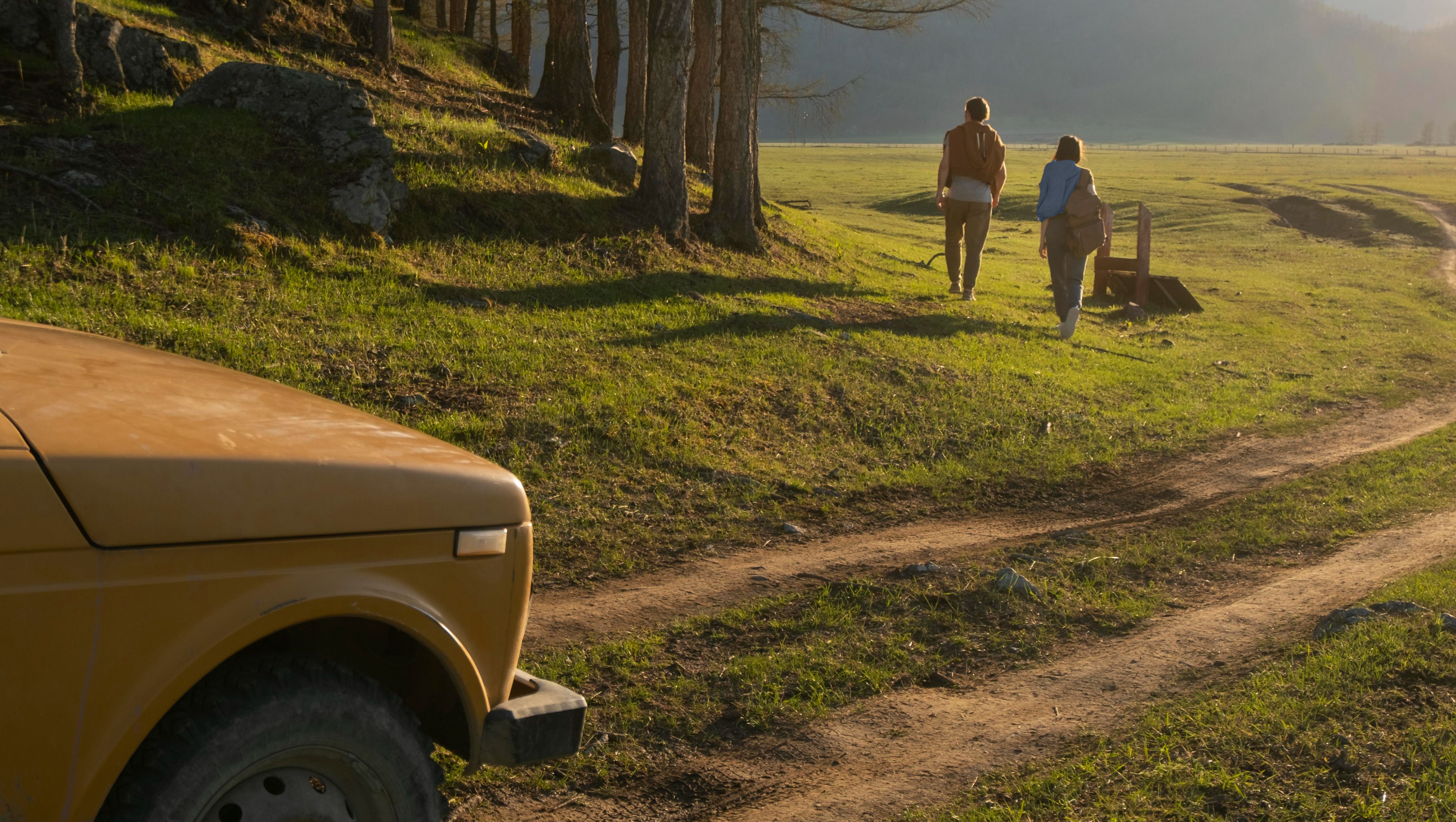 bil parkerad på skånska landsbygden och två personer tar en promenad